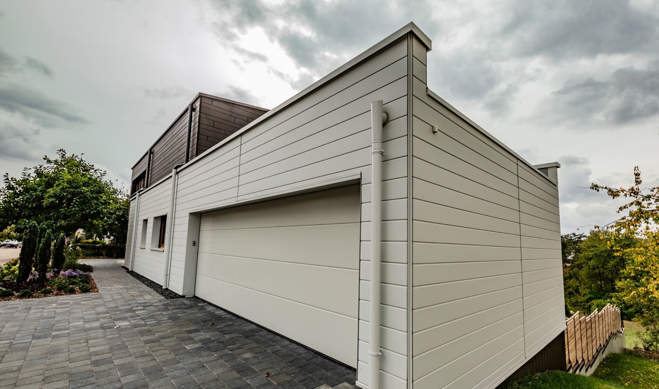 Garage cladding with horizontally installed PREFA siding in white together with the PREFA parapet outlet connector.