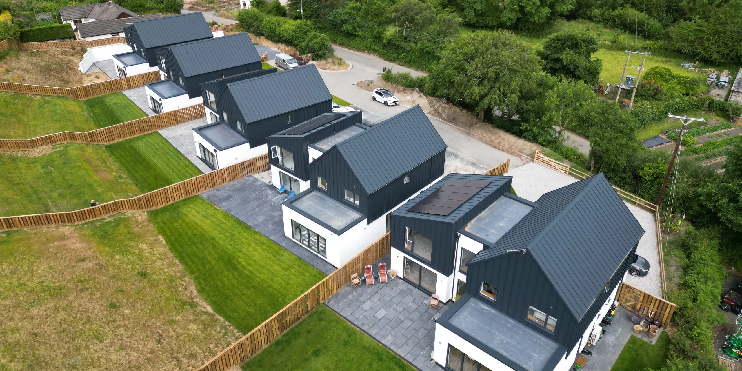 A bird's eye view of a detached housing development in Bridgerule, Devon, with PREFALZ standing seam P.10 anthracite as the uniform roof and facade material. The standing seam roofing made of high-quality and durable metal sheets provides a storm-proof and aesthetic solution over an area of approx. 1,250 m².