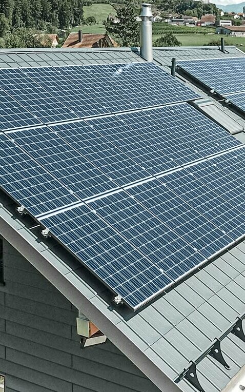 [Translate to English:] PREFA Dachplatte in der Farbe anthrazit mit einer montierten Photovoltaik-Anlage als Aufdach-Lösung.