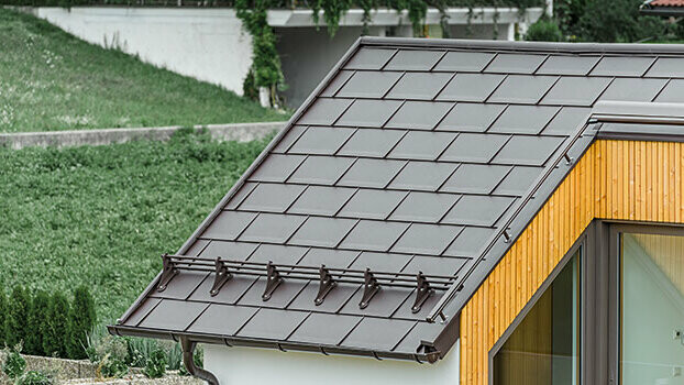 Roof with PREFA R.16 roof tiles in nut brown and snow guard system.