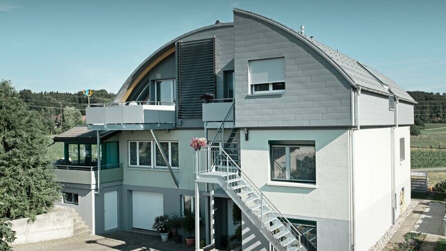 Home with barrel roof covered in PREFA roof tiles and Prefalz in P.10 light grey