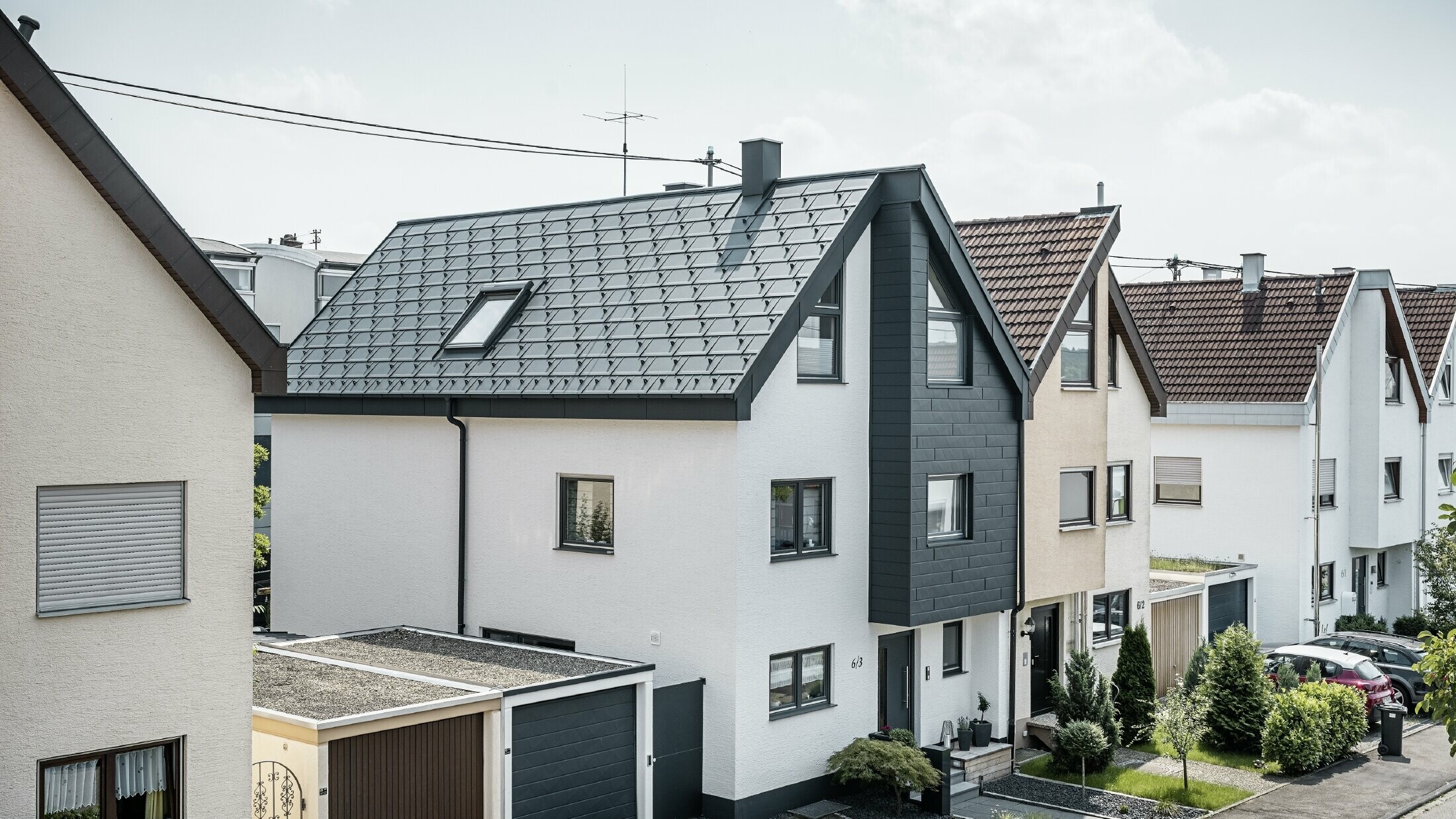 One semi-detached house has already been renovated, with a fresh white plaster façade, combined with a PREFA siding.X façade in anthracite. The roof was covered with PREFA roof tile R.16. The roof is drained via the square box gutter and the PREFA downpipe.