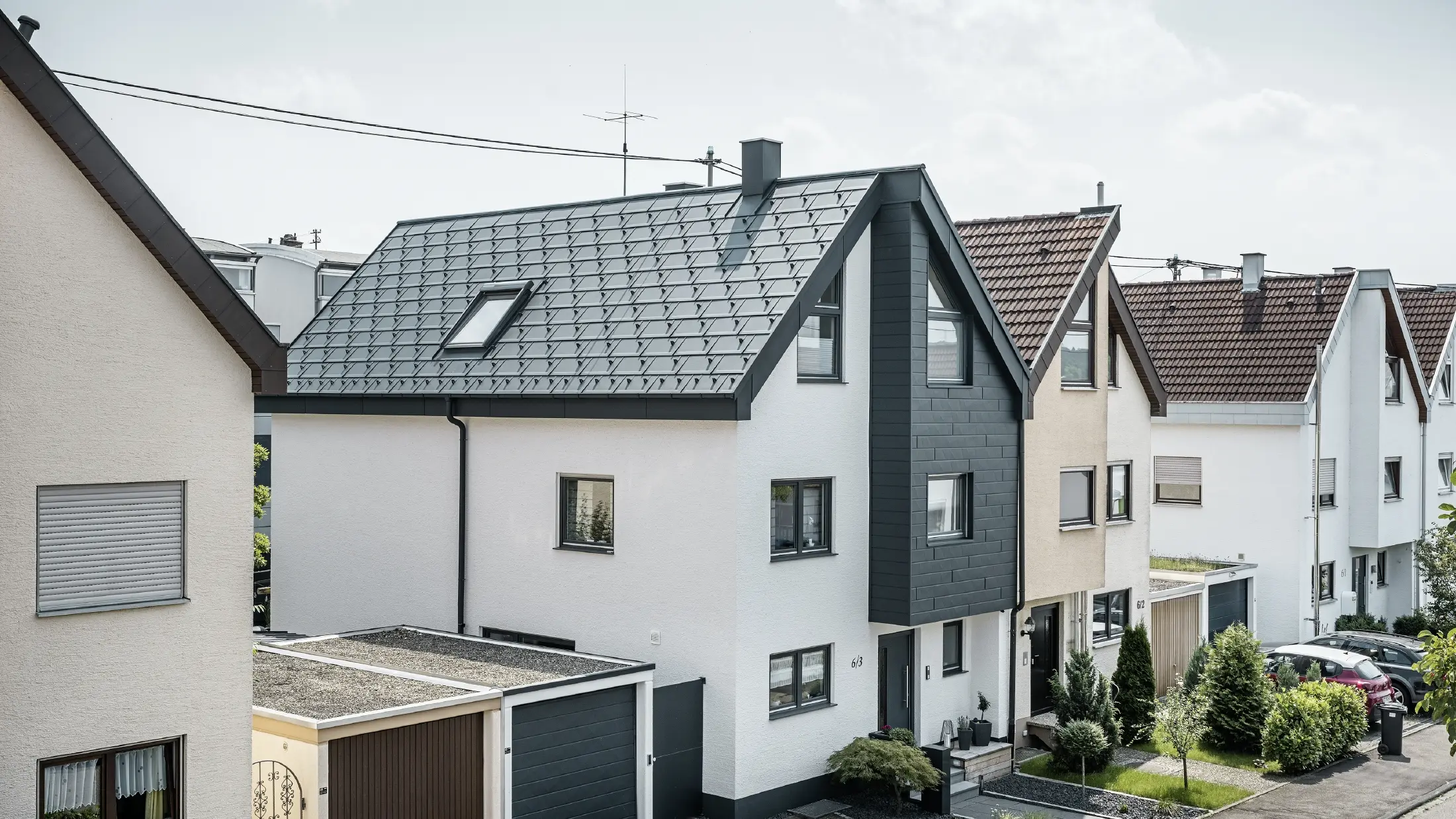 One semi-detached house has already been renovated, with a fresh white plaster façade, combined with a PREFA siding.X façade in anthracite. The roof was covered with PREFA R.16 roof tile. The roof is drained via the square box gutter and the PREFA downpipe.