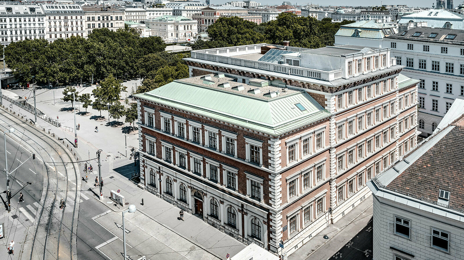 View of the protestant elementary school at Karlsplatz, Vienna. It is surrounded by buildings and trees.
