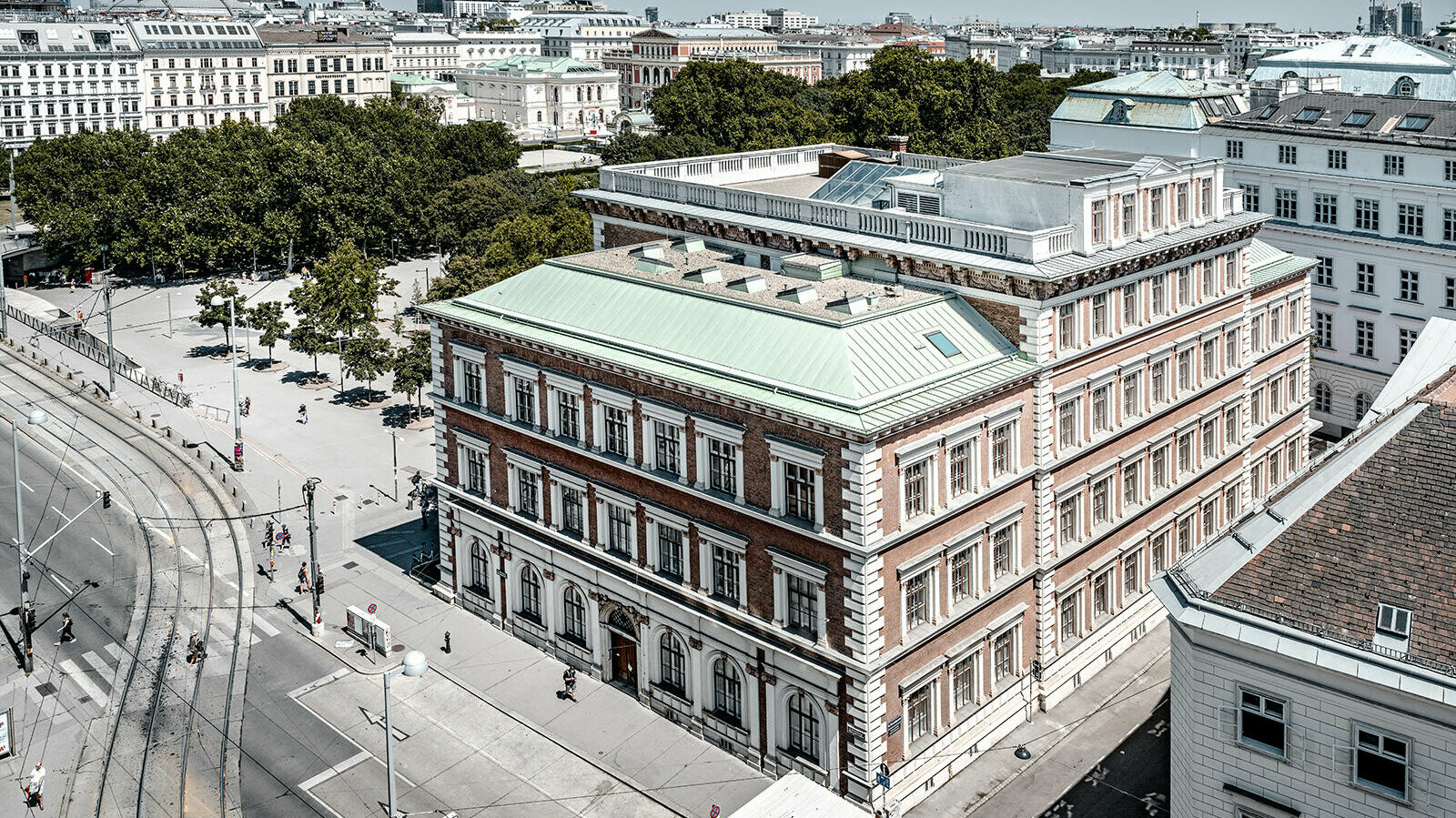 View of the protestant elementary school at Karlsplatz, Vienna. It is surrounded by buildings and trees.