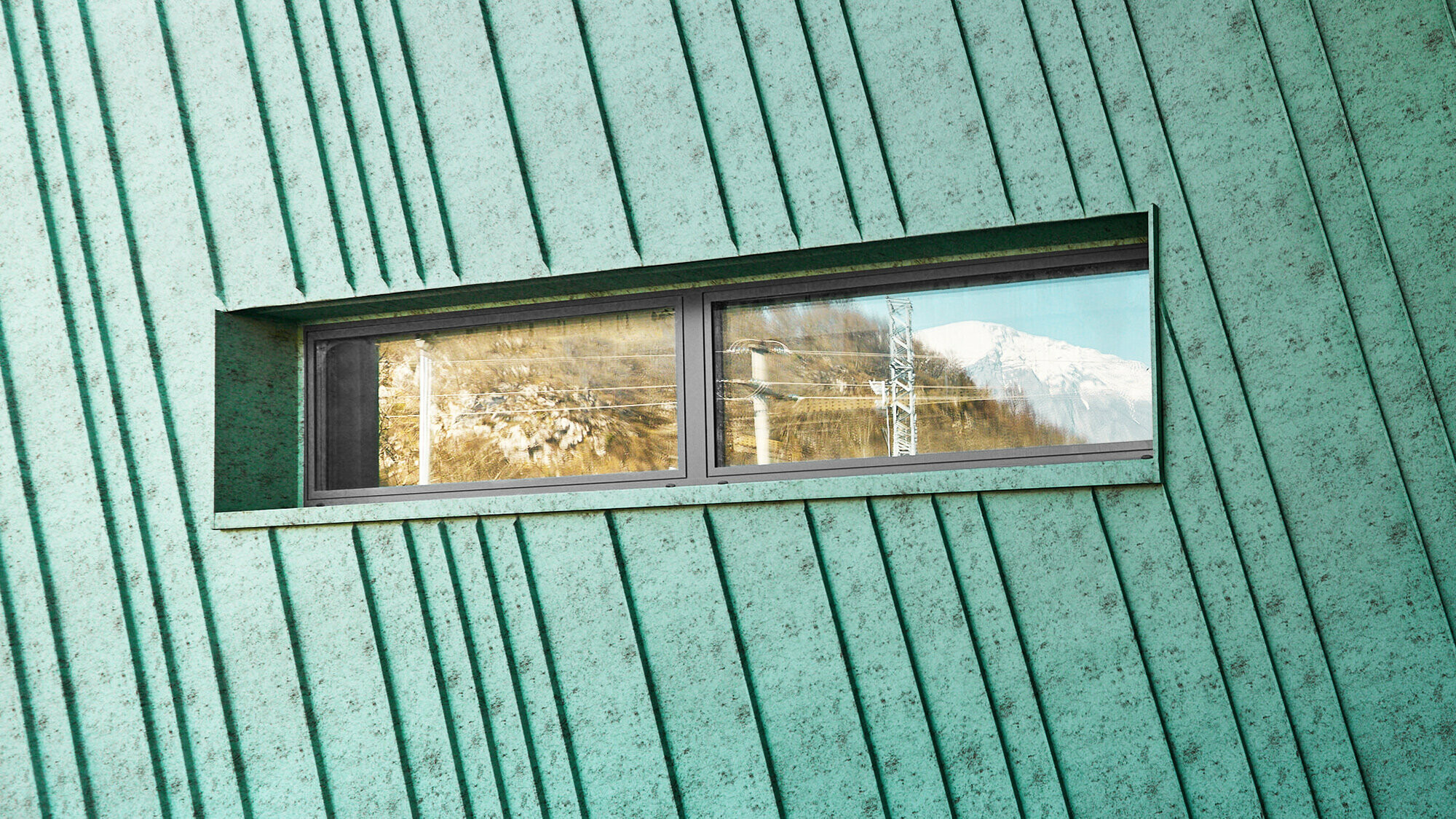 Detail with slightly slanted façade and a small, elongated window that reflects the mountains and electrical lines. Lateral view of the façade and glass front with an entrance. 