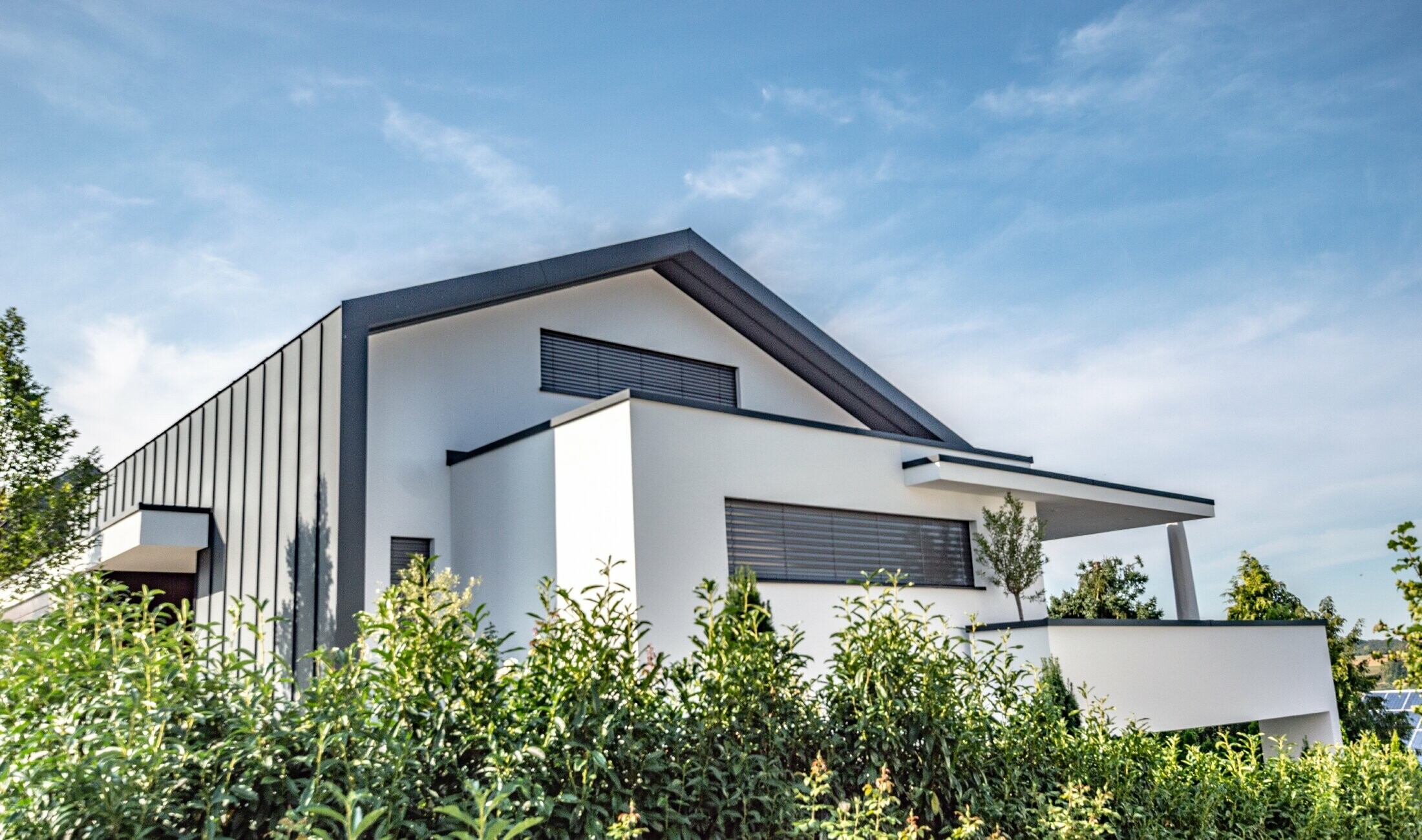 Modern detached house in which the roof cladding also extends over the façade as standing seam cladding. The colour used for the PREFA material is anthracite.