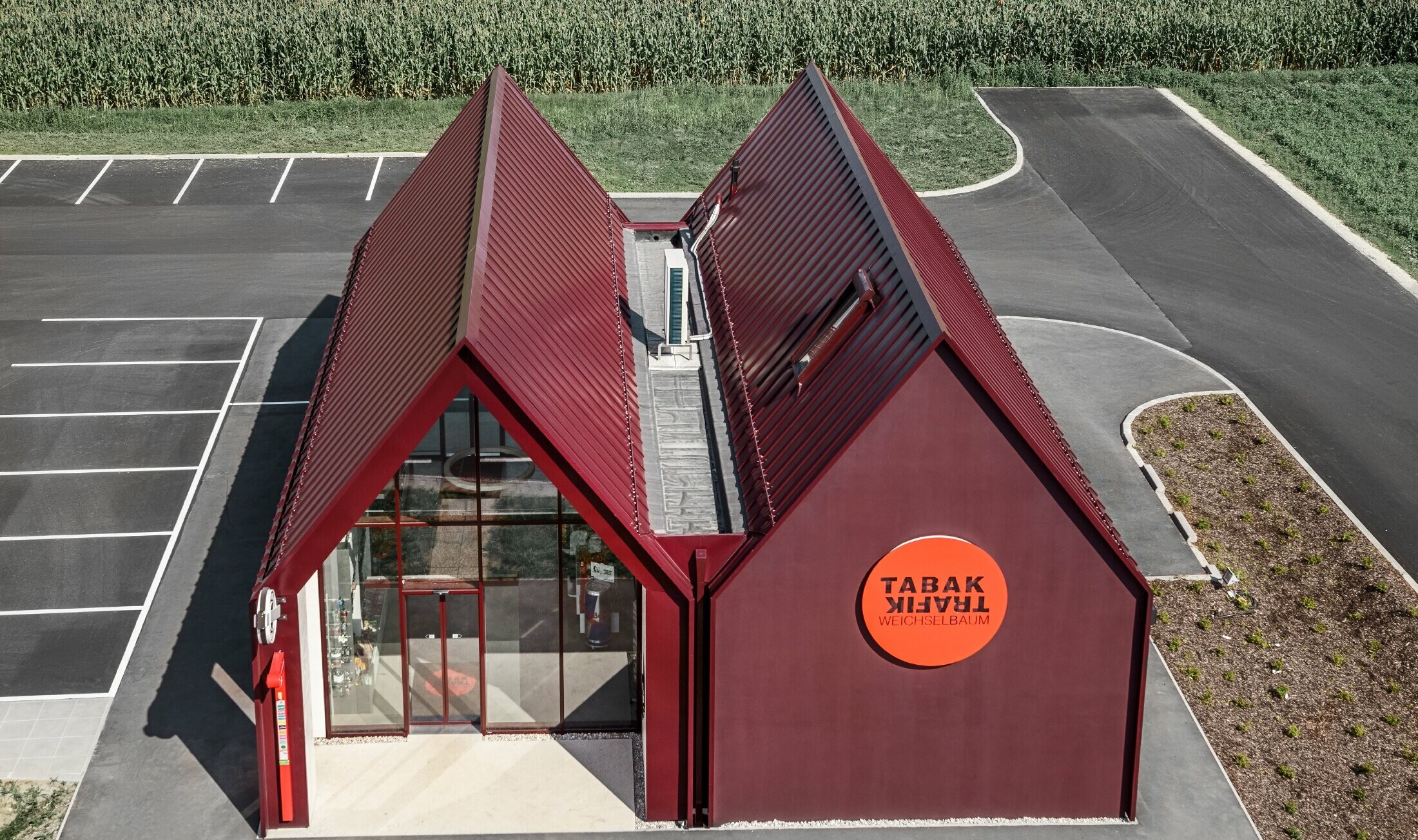 Modern tobacconist with gable roof (without overhanging eaves) and an aluminium coating by PREFA with standing and single lock standing seam in the special colour of black red