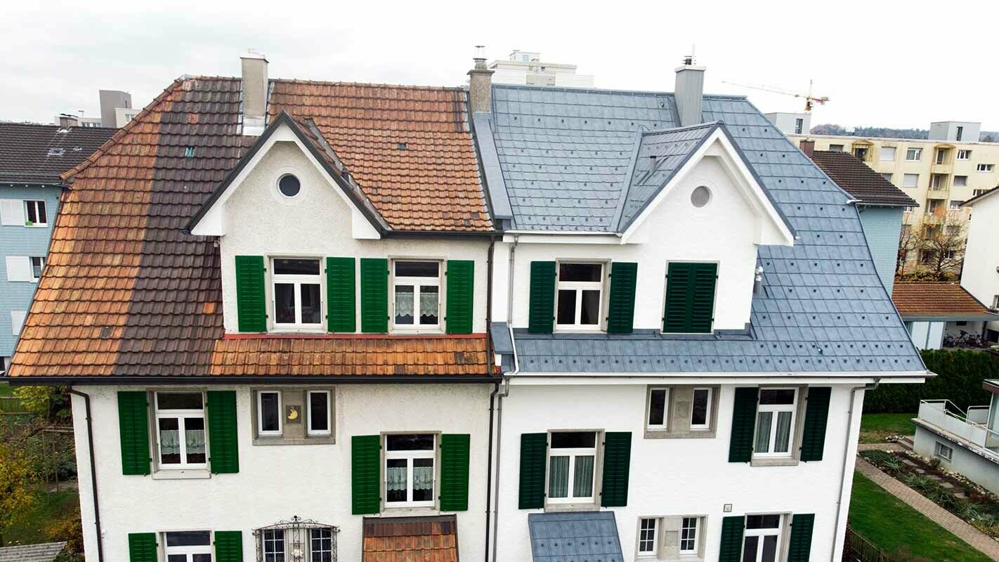 Semi-detached house in Switzerland; the left part of the building has not yet been renovated and is still covered in stained roof tiles. The right part of the building has been covered with PREFA roof tiles in stone grey.