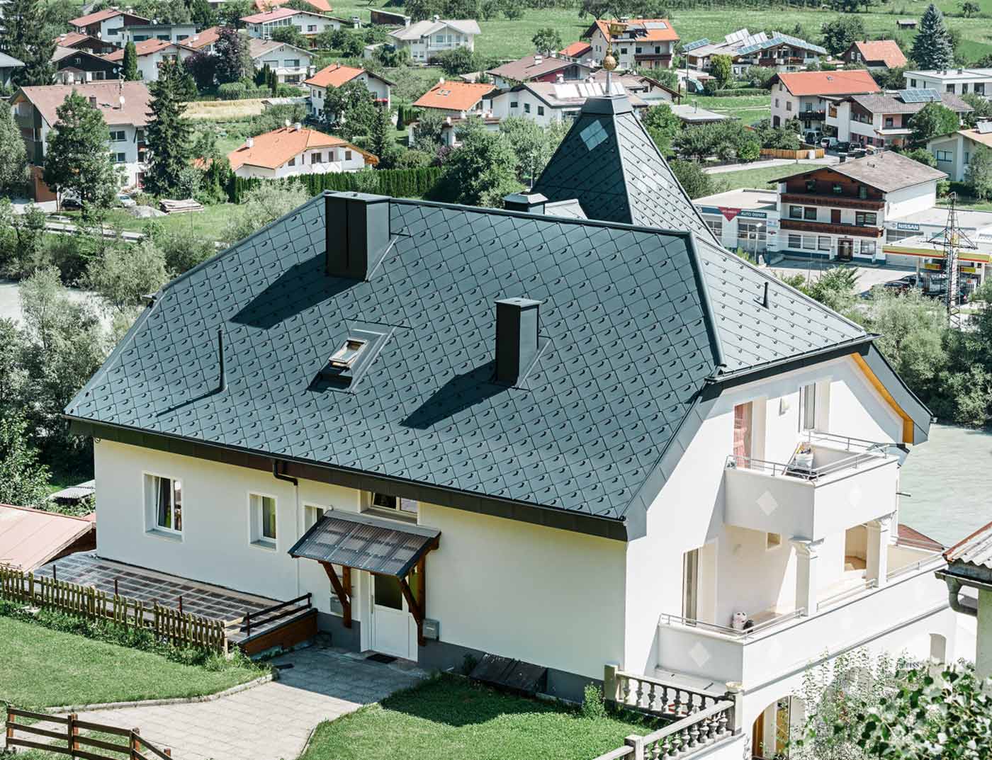 PREFA rhomboid roof tile 44 × 44 anthracite reference Half-hip roof with a tower, covered with the 44 × 44 aluminium rhomboid roof tiles in anthracite.
