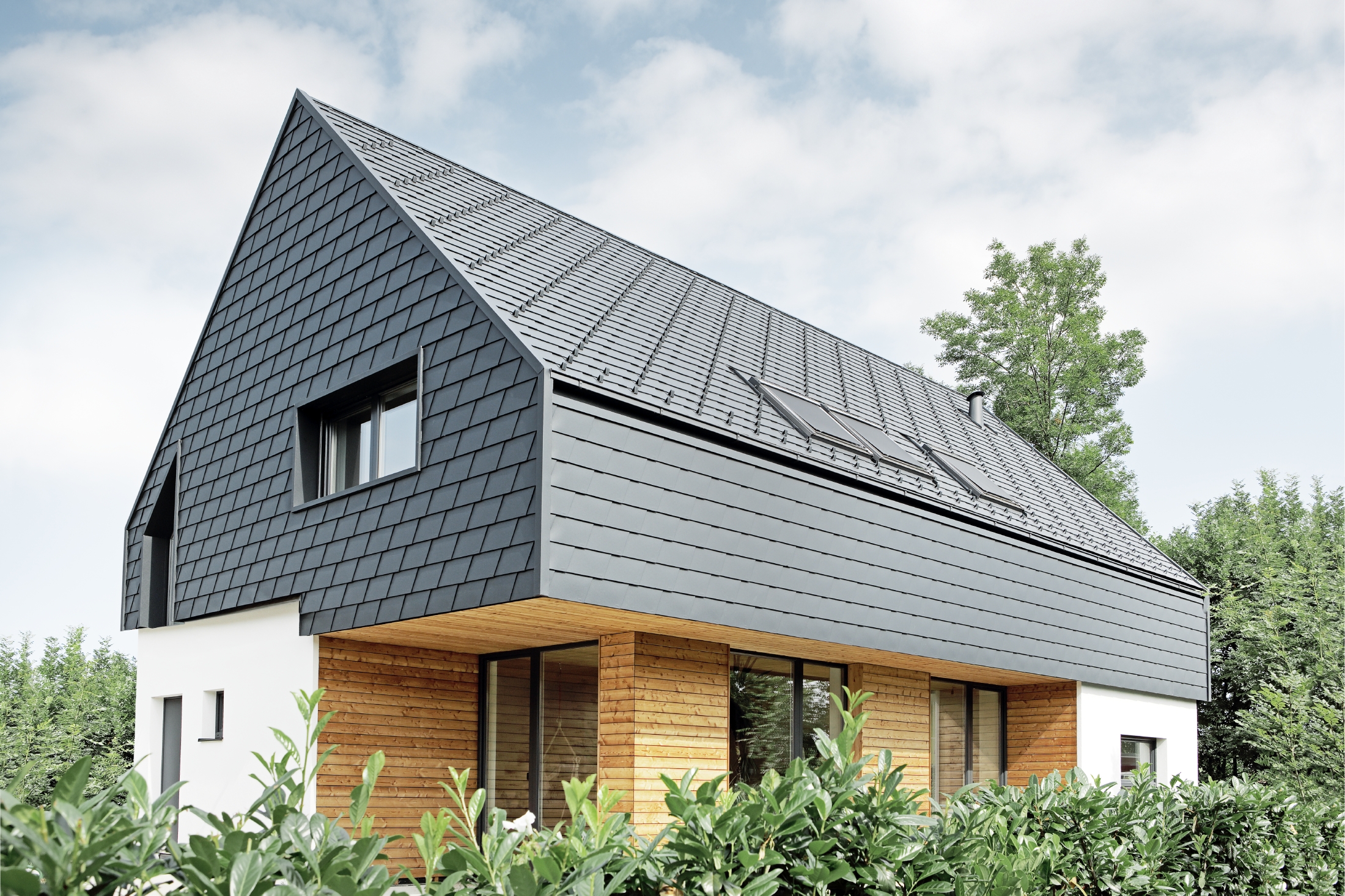 Detached house with gable roof, roofed with PREFA roof shingles in P.10 anthracite, the shingles were also installed on the façade on the upper floor and on the gable.